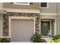 Close up of a townhome with a garage, featuring stone accents and a decorative front door at 10425 Yellow Spice Ct, Riverview, FL 33578