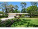 Charming single-story home with a lush front lawn and mature trees at 1431 Normandy Ln, Palm Harbor, FL 34683