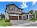 Elegant two-story home with a tile roof, stone accents, and a spacious three-car garage at 14421 Swiss Bridge Dr, Lithia, FL 33547