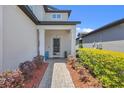 Inviting front entrance featuring a covered porch, well-maintained landscaping, and a paved walkway at 1949 Parterre Ave, Lutz, FL 33558