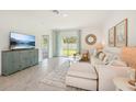 Bright living room with neutral tones, tile flooring, and sliding glass doors to the backyard at 32708 Winterwood Blvd, Wesley Chapel, FL 33543