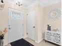 Bright foyer with a white front door, decorative mirror and cabinet, and a dark rug on wood floors at 7747 90Th N Way, Seminole, FL 33777