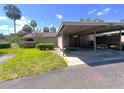 Carport view of a single Gathering home with a beige exterior, green lawn, and palm trees at 7939 Pine Dr # 7939, Temple Terrace, FL 33637