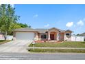 Well maintained single Gathering home with a manicured lawn, mature trees, and a neatly paved driveway to the garage at 1061 Archway Dr, Spring Hill, FL 34608