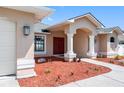 Inviting front entrance with a red double door, white columns, manicured landscaping, and decorative lighting at 1061 Archway Dr, Spring Hill, FL 34608