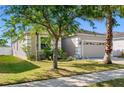 Attractive single-Gathering home featuring a manicured lawn, mature trees, and neutral exterior paint at 11207 Flora Springs Dr, Riverview, FL 33579