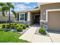 Inviting home exterior featuring stone accents, manicured landscaping, and a well-lit entryway at 16625 Goose Ribbon Pl, Wimauma, FL 33598
