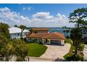 Stunning waterfront home with a tile roof, manicured lawn and paver driveway under a sunny blue sky at 2096 Tanglewood Ne Way, St Petersburg, FL 33702