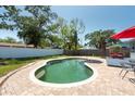 Relaxing backyard oasis showcasing an in-ground pool surrounded by a paved patio and shaded by mature trees at 3066 19Th Sw Pl, Largo, FL 33774