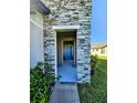 Front entry way with a stone facade and a blue front door at 5154 Brickwood Rise Dr, Wimauma, FL 33598