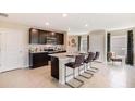 Modern kitchen featuring dark cabinets, stainless steel appliances, and seating for three at 5527 Warrington Town Path, Wesley Chapel, FL 33545