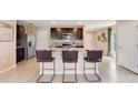 Modern kitchen featuring dark cabinets, stainless steel appliances, and seating for three at 5527 Warrington Town Path, Wesley Chapel, FL 33545