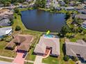 Aerial view of a home with a screened pool, lush backyard and tranquil lake at 6056 Fall River Dr, New Port Richey, FL 34655