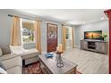 Cozy living room features wood-look flooring, decorative rug, and large windows for natural light at 1019 Goshen Rd, Tarpon Springs, FL 34689