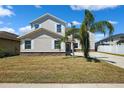 Charming two-story home with stone accents, lush lawn, and mature palm trees against a clear blue sky at 11907 Streambed Dr, Riverview, FL 33579