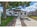 Beautifully renovated home featuring a modern exterior, manicured lawn, and well-lit walkway, with a striking tree to the side at 1514 55Th N Ave, St Petersburg, FL 33703