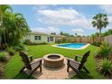 Landscaped backyard featuring a pool, fire pit, lush lawn, and tropical plants at 1758 Southview Rd, Largo, FL 33770