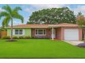 Charming single-story home with lush green lawn, mature trees, and colorful flower beds at 1758 Southview Rd, Largo, FL 33770