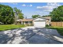 Well-maintained ranch-style home with a long driveway, two-car garage, and lush landscaping at 17605 Simmons Rd, Lutz, FL 33548