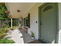Inviting front porch with a light green front door, stone accents, and a cozy seating area at 17605 Simmons Rd, Lutz, FL 33548