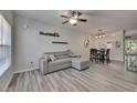 Inviting living room with a comfortable gray sofa, a modern ceiling fan, and wood-look flooring at 2362 Lake Woodberry Cir, Brandon, FL 33510