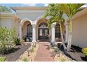 Inviting front porch with tiled walkway, columns, double front doors, and landscaped garden beds at 3009 Sheehan Dr, Land O Lakes, FL 34638