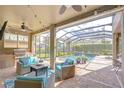 Covered lanai with outdoor kitchen, fireplace and seating area overlooking the screened-in pool at 6112 Ibispark Dr, Lithia, FL 33547