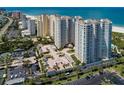 An aerial view showcases luxurious condos, parking, tennis courts and lush landscaping near pristine beaches at 1180 Gulf Blvd # 202, Clearwater Beach, FL 33767
