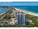 An aerial view displays stunning condos with a beachfront location, showcasing the pool, parking and coastal views at 1180 Gulf Blvd # 202, Clearwater Beach, FL 33767