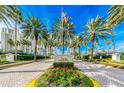 Beautiful condominium entrance featuring lush landscaping with mature palm trees, red flowers, and clear skies at 1180 Gulf Blvd # 202, Clearwater Beach, FL 33767