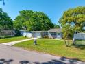 Well-kept single-story home with lush lawn, mature tree, and charming white picket fence at 1290 Bertland Way, Clearwater, FL 33755