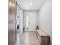 Bright foyer featuring ceramic tile flooring, bench seating, and barn door entry at 13757 Wineberry Dr, Dade City, FL 33525