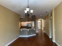 Open-concept living space with hardwood floors, chandelier, and views of the kitchen and entryway at 1415 Saddle Gold Ct, Brandon, FL 33511