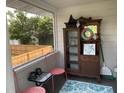 Enclosed porch includes vintage cabinet, decor, and view of the fenced backyard at 1626 27Th N Ave, St Petersburg, FL 33713