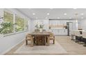Bright dining area featuring a large wood table, modern chairs, and a view into the kitchen at 1905 Oro Ct, Clearwater, FL 33764