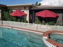 Inviting swimming pool and spa with red umbrellas offering shade at 2172 Harbor View Dr, Dunedin, FL 34698