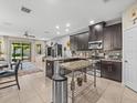 Modern kitchen with dark cabinets, granite countertops, stainless steel appliances, and an eat-in island at 602 Cabernet Way, Oldsmar, FL 34677
