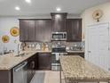 Well-lit kitchen featuring granite countertops, stainless steel appliances, and stylish brown cabinets at 602 Cabernet Way, Oldsmar, FL 34677