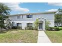 Exterior view of a light grey townhome with a well-kept lawn and sidewalk leading to the entrance at 7303 E Bank Dr, Tampa, FL 33617