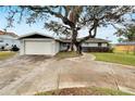 Traditional-style home with mature trees, a 2-car garage, and a curved walkway leading to the front door at 828 Bayshore Dr, Tarpon Springs, FL 34689