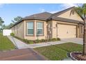 Well-kept house featuring a tan exterior, two-car garage, and manicured lawn, plus attractive landscaping at 8975 Southern Charm Cir, Brooksville, FL 34613