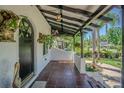 Inviting front porch featuring Spanish tile flooring, a hanging lantern, and lush greenery with a black door and white columns at 1175 Jackson Rd, Clearwater, FL 33755