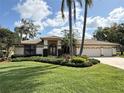 Charming home with lush landscaping, an arched entryway, and a two-car garage at 1311 Fallsmeade Ct, Oldsmar, FL 34677