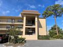 Exterior shot of multi-level building with balconies, a tree, and partial driveway at 1370 Heather Ridge Blvd # 310, Dunedin, FL 34698