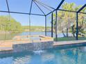 Relaxing private pool with a spa and a screened enclosure overlooking a serene lake at 2679 Saddlewood Ln, Palm Harbor, FL 34685