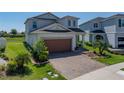 Inviting two-story home featuring a brick paved driveway and lush green lawn at 34135 White Fountain Ct, Wesley Chapel, FL 33545