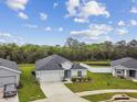 New single-story home featuring an attached two-car garage, verdant lawn, and white fencing at 7164 Twisting Pines Loop, Zephyrhills, FL 33541