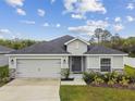 Single-story home boasts a two-car garage, appealing stone accents, and a well-kept front yard at 7164 Twisting Pines Loop, Zephyrhills, FL 33541