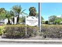 Heather Lake Condominiums sign amidst manicured hedges and palm trees at 940 Virginia St # 304, Dunedin, FL 34698