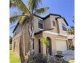 Attractive two-story home with a two-car garage, complemented by mature palm trees and manicured shrubbery at 12717 Lemon Pepper Dr, Riverview, FL 33578